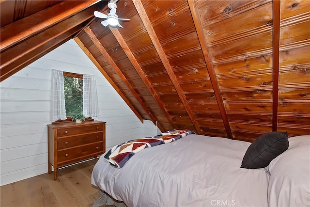 bedroom featuring lofted ceiling, wooden walls, and wood-type flooring