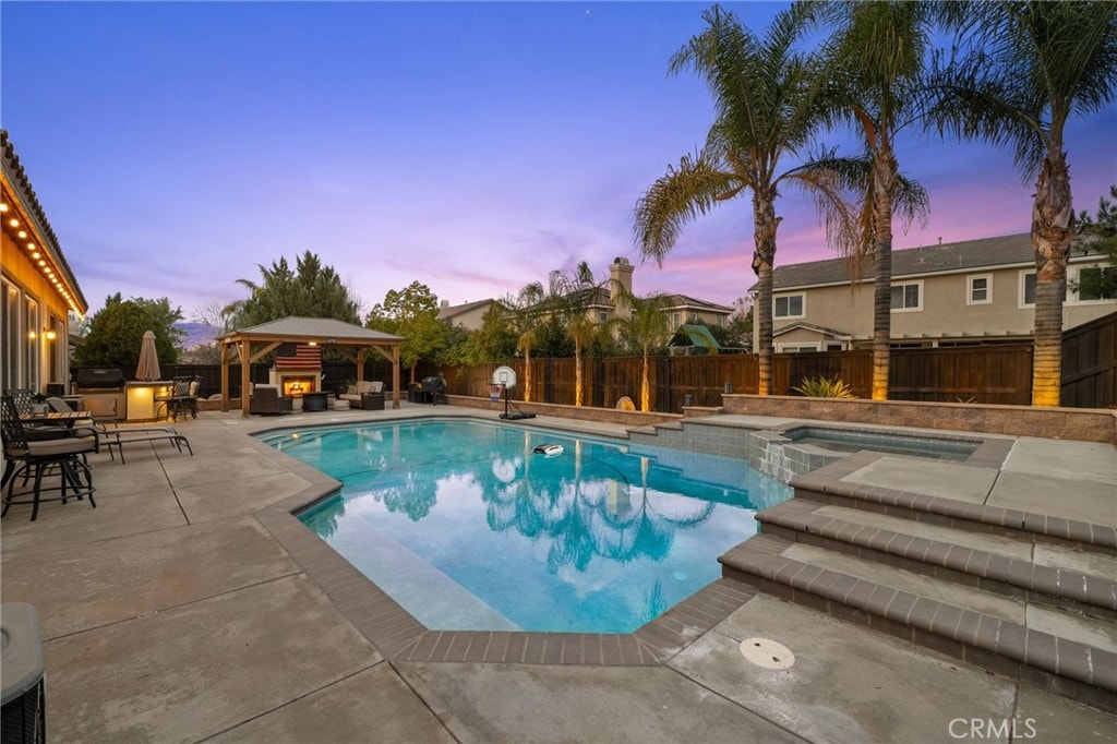 pool at dusk featuring area for grilling, a gazebo, and a patio