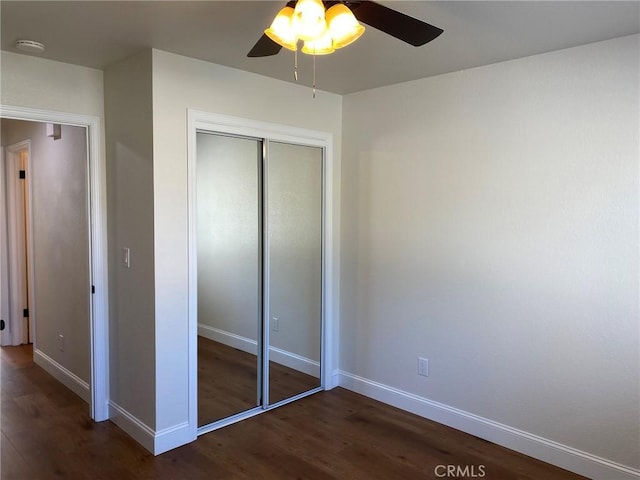 unfurnished bedroom with dark wood-type flooring, ceiling fan, and a closet