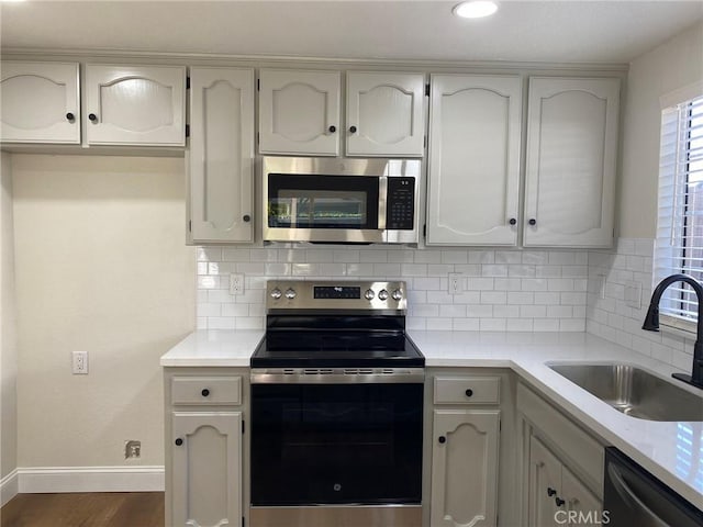 kitchen with sink, white cabinetry, stainless steel appliances, dark hardwood / wood-style flooring, and decorative backsplash