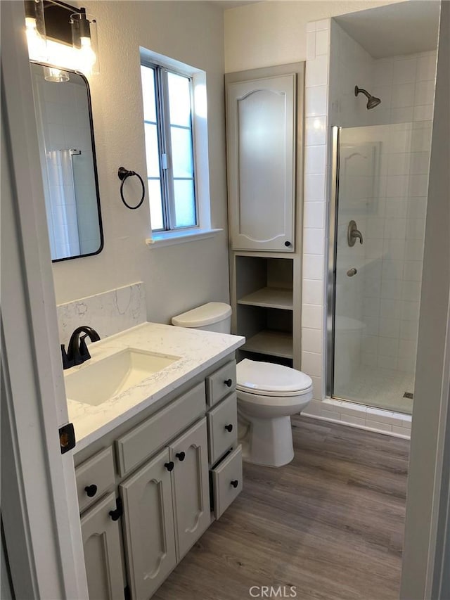 bathroom featuring walk in shower, vanity, toilet, and hardwood / wood-style flooring