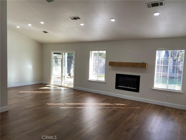 unfurnished living room with a textured ceiling and dark hardwood / wood-style flooring