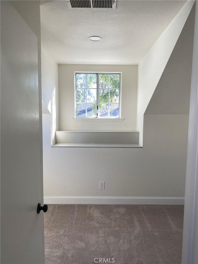 bonus room with dark carpet and a textured ceiling