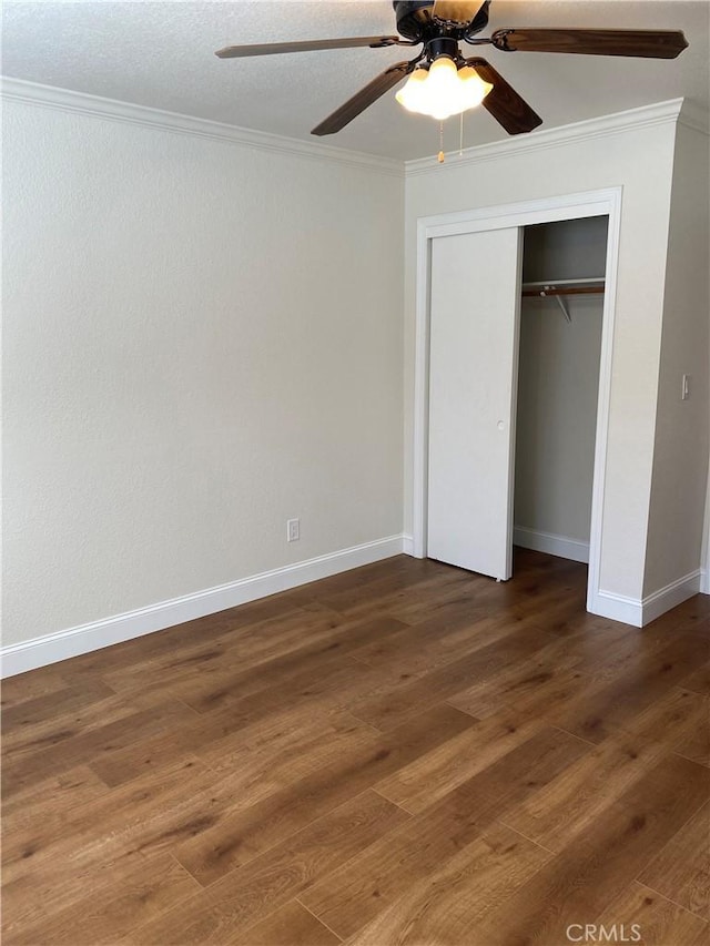 unfurnished bedroom with crown molding, dark hardwood / wood-style floors, ceiling fan, and a closet