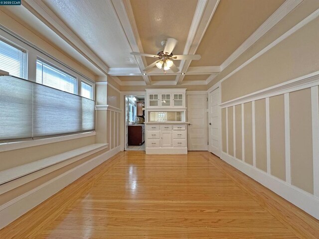 interior space featuring coffered ceiling, crown molding, beamed ceiling, ceiling fan, and light hardwood / wood-style floors