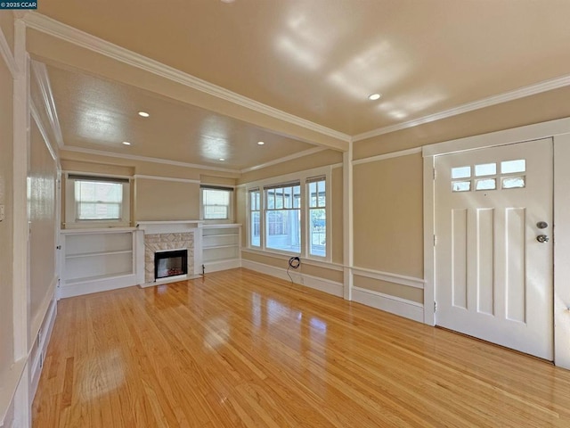 unfurnished living room featuring wood-type flooring, ornamental molding, and a fireplace