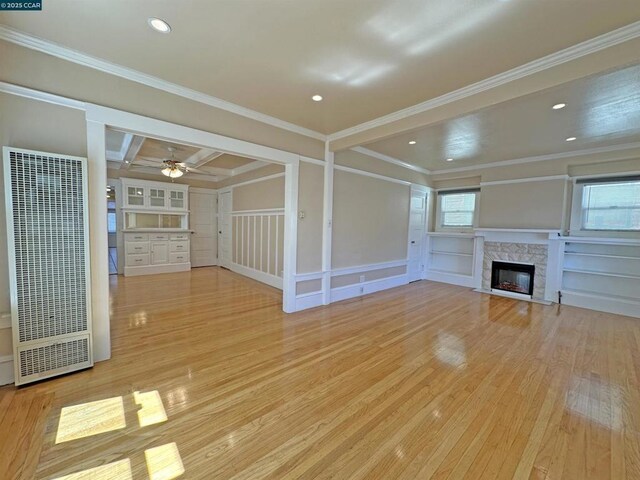 unfurnished living room featuring light hardwood / wood-style flooring, ceiling fan, coffered ceiling, a fireplace, and ornamental molding