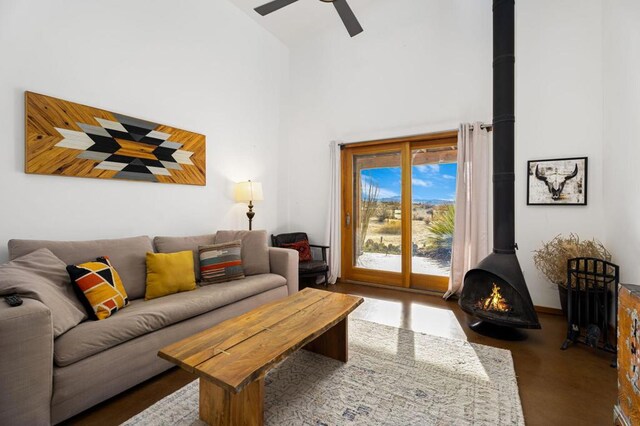 living room featuring ceiling fan, a high ceiling, and a wood stove