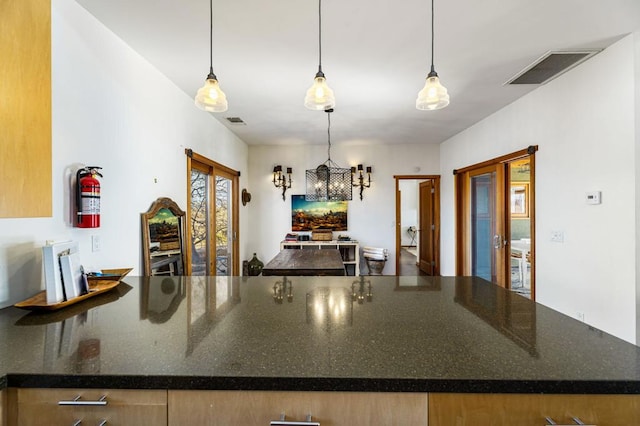 kitchen featuring french doors, dark stone countertops, and decorative light fixtures