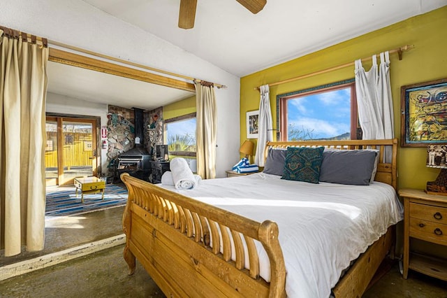 bedroom featuring lofted ceiling, a wood stove, access to exterior, and ceiling fan