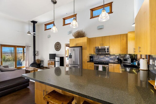 kitchen with hanging light fixtures, stainless steel appliances, kitchen peninsula, and a high ceiling