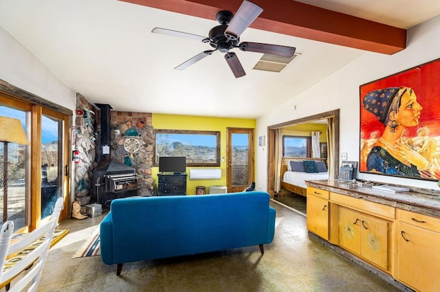 living room featuring ceiling fan, lofted ceiling with beams, and a wood stove