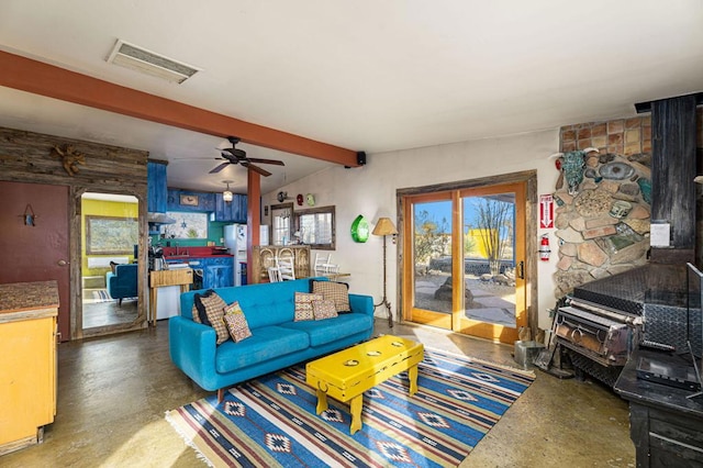 living room with vaulted ceiling with beams, concrete floors, ceiling fan, and a wood stove