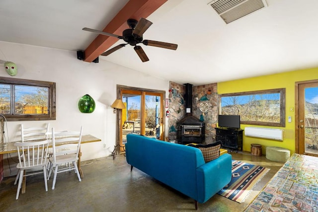 living room with an AC wall unit, a wood stove, vaulted ceiling with beams, and ceiling fan