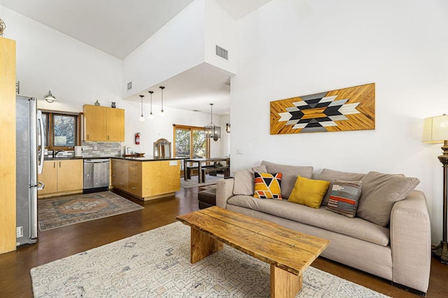 living room featuring a notable chandelier, plenty of natural light, and a high ceiling