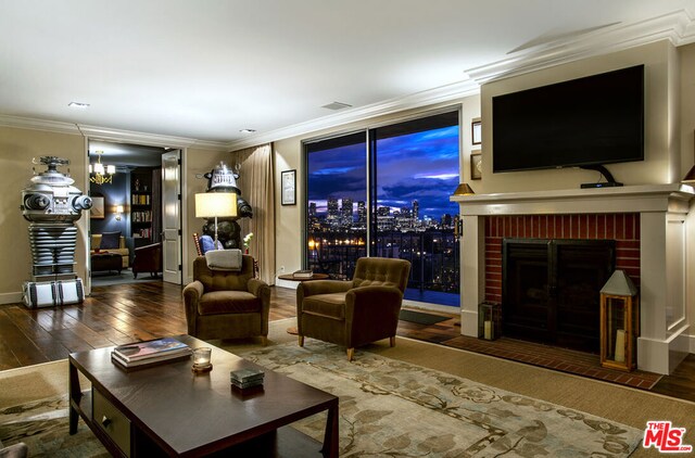 living room featuring ornamental molding, wood-type flooring, and a brick fireplace