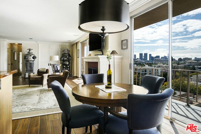 dining space with hardwood / wood-style flooring, ornamental molding, and expansive windows