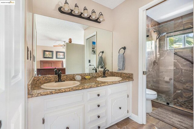 bathroom featuring vanity, a tile shower, ceiling fan, and toilet