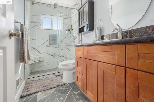 bathroom with vanity, toilet, and a tile shower