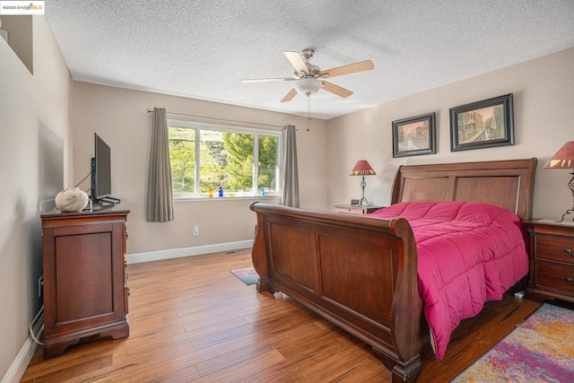 bedroom featuring ceiling fan, a textured ceiling, and light wood-type flooring