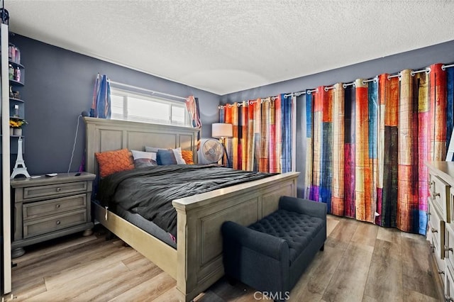 bedroom with a textured ceiling and light wood-type flooring