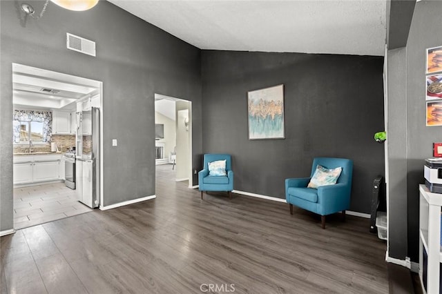 unfurnished room featuring wood-type flooring, lofted ceiling, and sink