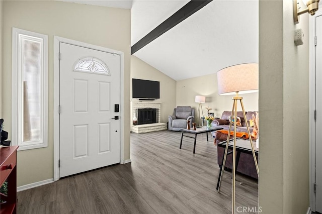 entryway featuring a brick fireplace, hardwood / wood-style flooring, a wealth of natural light, and lofted ceiling with beams