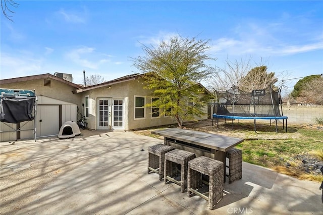 wooden deck with a trampoline, a storage shed, a patio area, and an outdoor bar