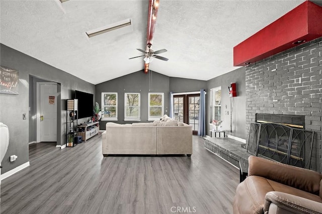 living room featuring a brick fireplace, wood-type flooring, a textured ceiling, and vaulted ceiling