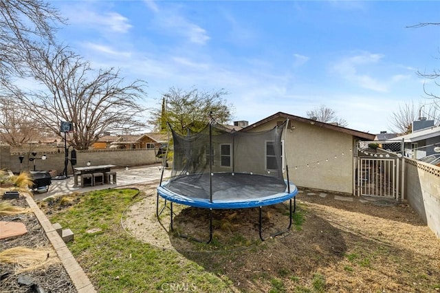 back of property with a trampoline and a patio