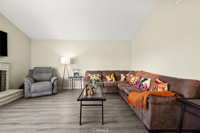 living room featuring hardwood / wood-style flooring, vaulted ceiling, and a brick fireplace