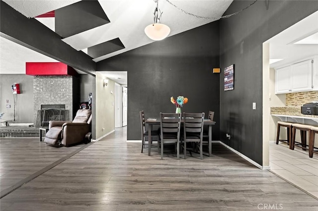 dining area featuring lofted ceiling with beams, a brick fireplace, and hardwood / wood-style floors