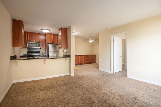 kitchen featuring a kitchen bar, sink, light carpet, appliances with stainless steel finishes, and kitchen peninsula