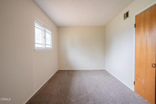 empty room with carpet floors and a textured ceiling