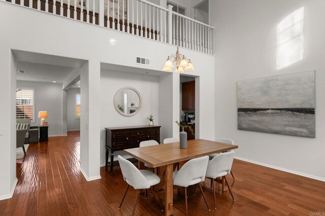 dining room with wood-type flooring, a chandelier, and a high ceiling