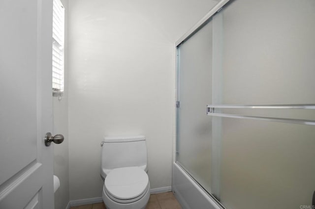 bathroom with bath / shower combo with glass door, toilet, and tile patterned flooring