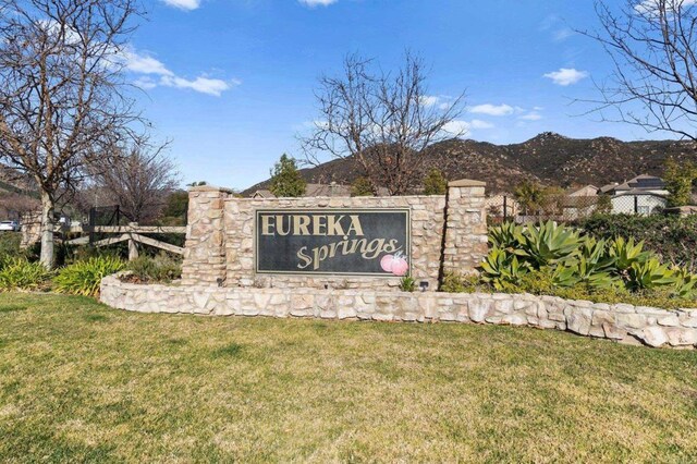 community / neighborhood sign with a mountain view and a yard