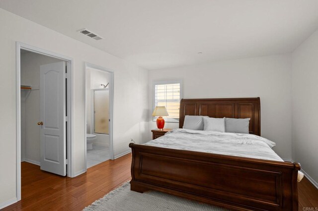 bedroom featuring wood-type flooring, a walk in closet, and connected bathroom