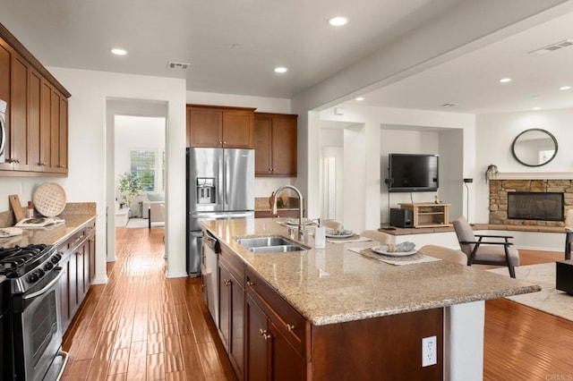 kitchen featuring appliances with stainless steel finishes, hardwood / wood-style floors, sink, a kitchen bar, and a center island with sink