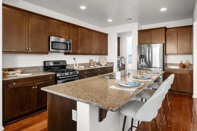 kitchen with stainless steel appliances, a breakfast bar area, and a center island with sink