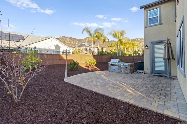 view of yard featuring an outdoor kitchen, a mountain view, and a patio