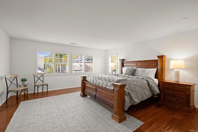 bedroom with multiple windows and dark hardwood / wood-style floors