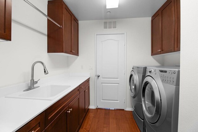 laundry area with cabinets, washing machine and clothes dryer, dark hardwood / wood-style floors, and sink