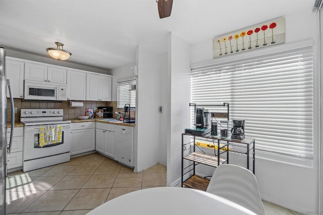 kitchen featuring light tile patterned flooring, tasteful backsplash, sink, white cabinets, and white appliances