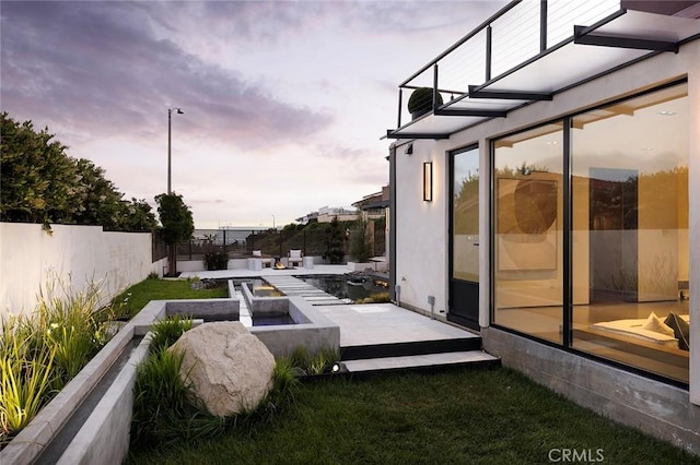 yard at dusk with a balcony and an outdoor fire pit