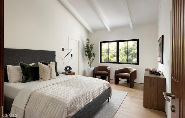 bedroom with lofted ceiling with beams and light hardwood / wood-style floors