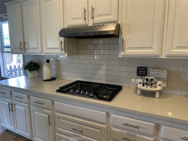 kitchen with decorative backsplash, black gas stovetop, light stone countertops, and white cabinets