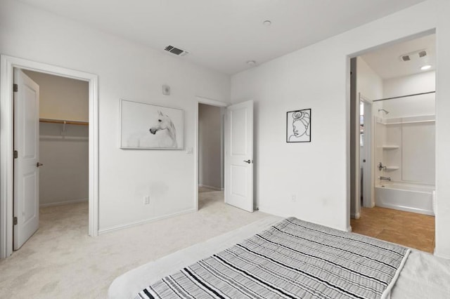 carpeted bedroom with a walk in closet, a closet, and ensuite bathroom