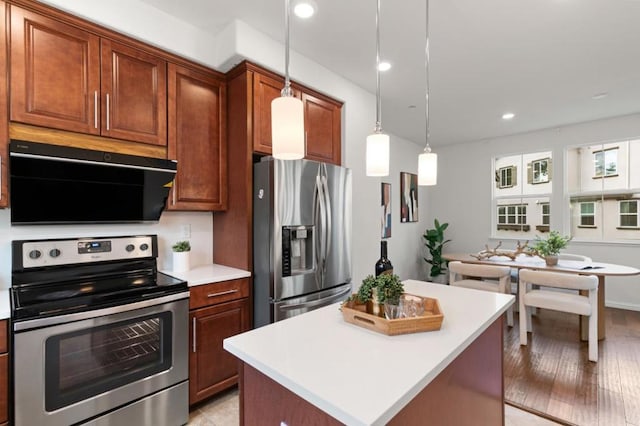 kitchen featuring appliances with stainless steel finishes, ventilation hood, hanging light fixtures, a center island, and light hardwood / wood-style flooring