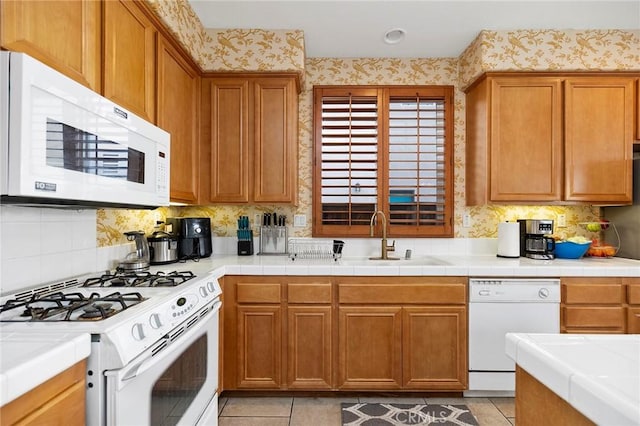 kitchen featuring tile countertops, sink, decorative backsplash, light tile patterned floors, and white appliances